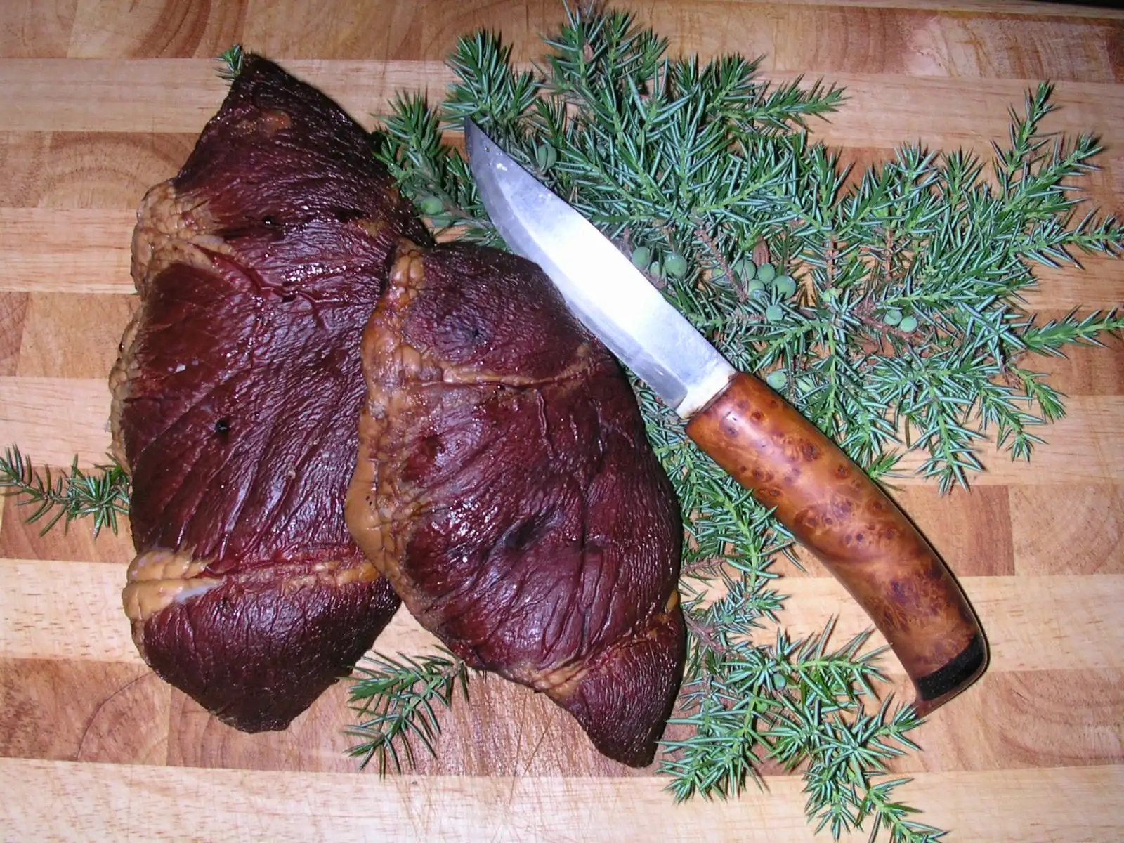 Rökt hjorthjärta på skärbräda med kniv och enris